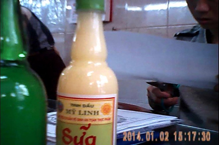 Người nhân viên vừa đánh máy nhãn sản phẩm, lấykéo cắt, chuẩn bị dán lên thân chai tinh dầu.