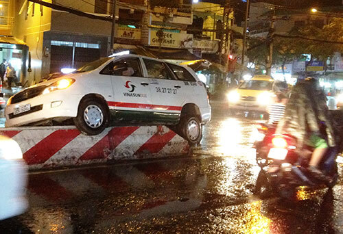 Tránh xe máy, taxi leo lên trên dải phân cách trong mưa