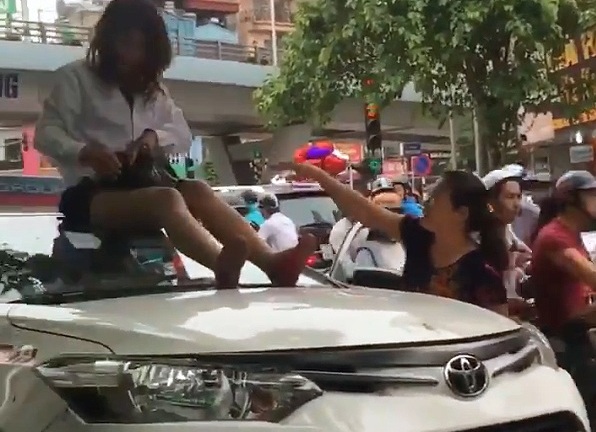 Nữ tài xế taxi mặc váy ngồi nóc ô tô chống đối CSGT