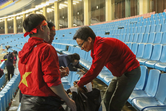 Hình ảnh Phó Thủ tướng Vũ Đức Đam dọn rác trên sân Mỹ Đình sau trận chung kết gây xúc động