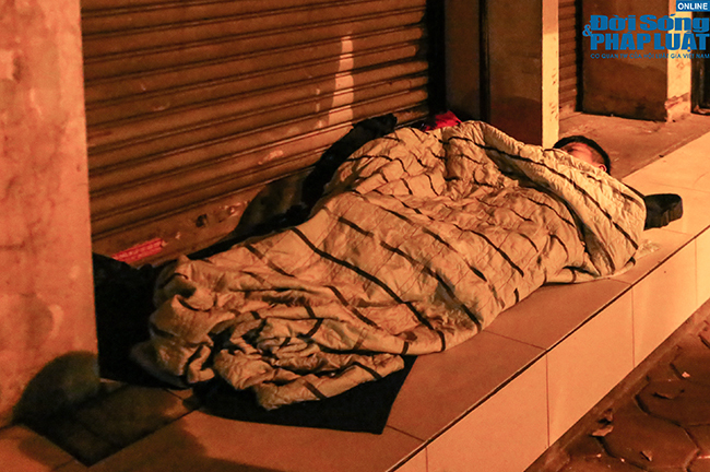 Người vô gia cư ở Hà Nội co ro, trùm áo mưa ngủ trên vỉa hè trong đêm mưa rét