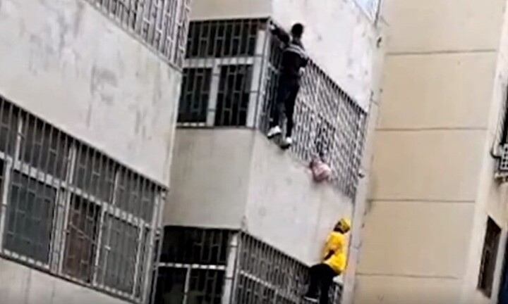 Clip: Nhân viên giao hàng tay không leo 3 tầng lầu cứu đỡ bé gái mắt kẹt ngoài song sắt căn hộ