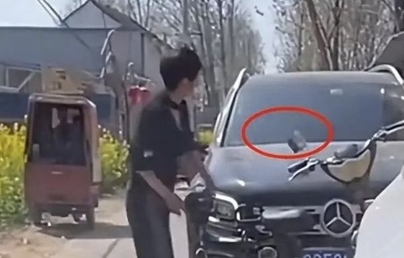 Người phụ nữ bẻ gãy kính chiếu hậu của chiếc Mercedes-Benz, sau đó nhặt gạch đá đập mạnh vào xe.