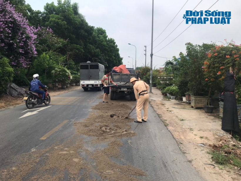 Cán bộ Đội CSGT đường bộ số 15 cùng nhân dân rải cát khắc phục vệ dầu trên đường gom Võ Nguyên Giáp sáng 29/5