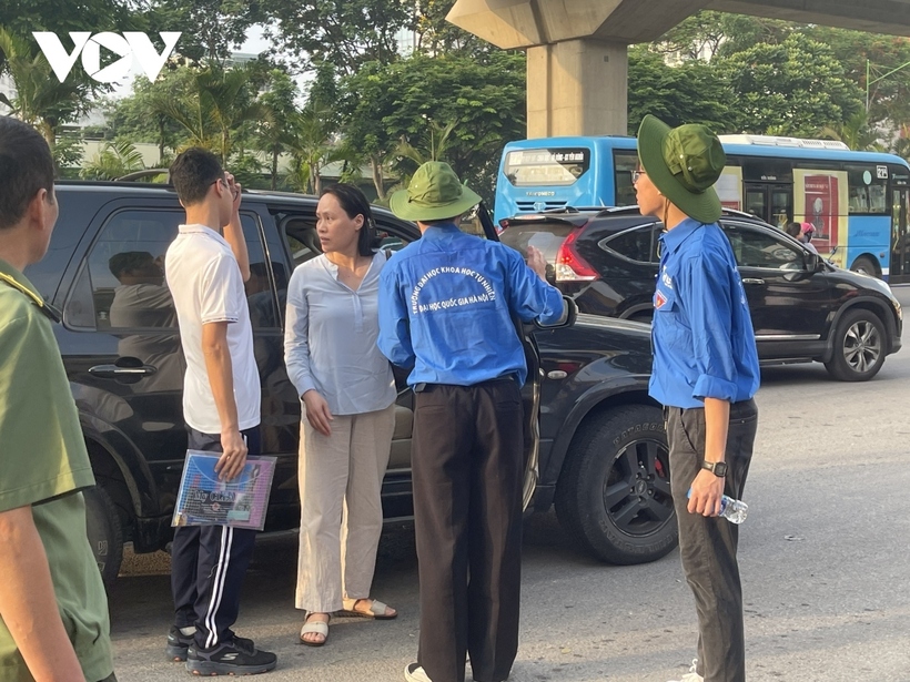 Hàng trăm phụ huynh học sinh đứng đợi con trước cổng trường mặc dù được các bạn sinh viên tình nguyện của trường ra sức kêu gọi không tập trung đông người.
