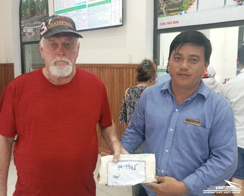 Hành khách (áo đỏ) nhận lại ví cùng toàn bộ tài sản bỏ quên trên tàu. Ảnh: VNR
