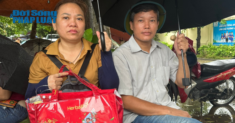 Vợ chồng chị Hoàng Bích Ngọc (phụ huynh em Nguyễn Khánh Duy, trường THCS Phú La) đội mưa để tiếp sức con trai chinh phục môn Toán.