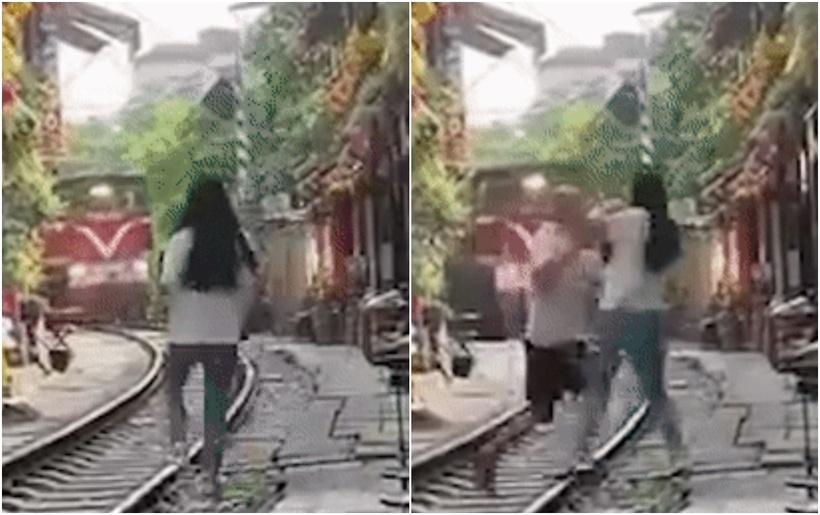 Nữ du khách lao đường ray để chụp ảnh thì được ông H. lao đến kéo vào trong vỉa hè. (Ảnh cắt từ clip)