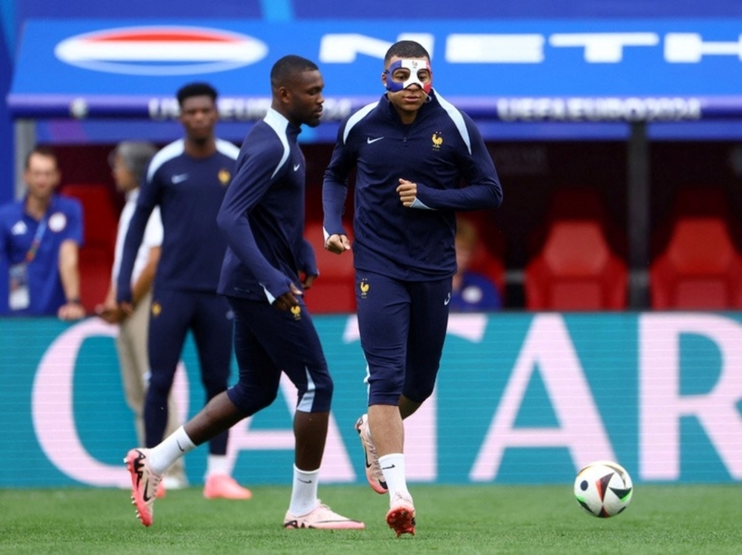 Mbappe mang mặt nạ bảo vệ khi ra sân tập luyện cùng các đồng đội. Ảnh: Reuters