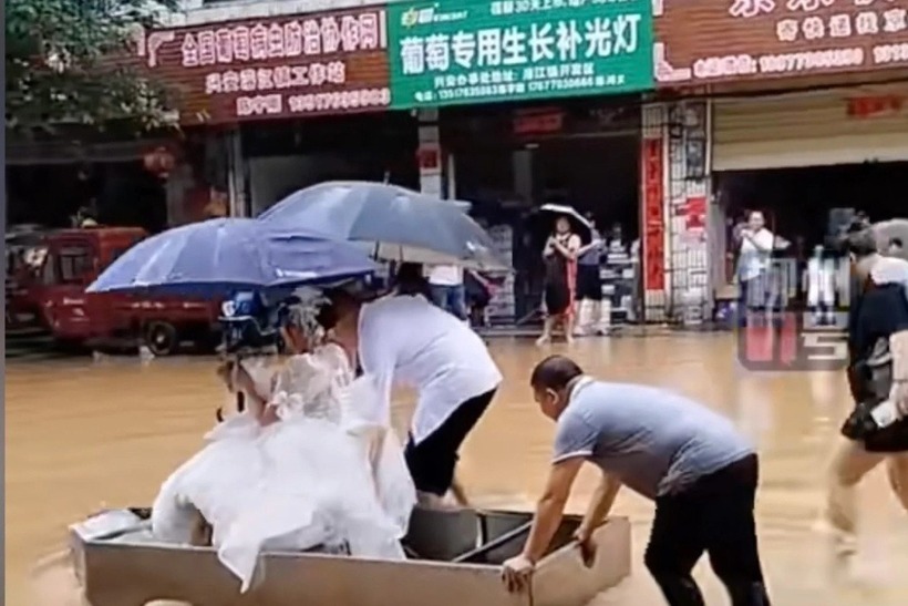 Chú rể và bố vợ thay nhau chèo thuyền đưa cô dâu về dinh. Ảnh: SCMP.