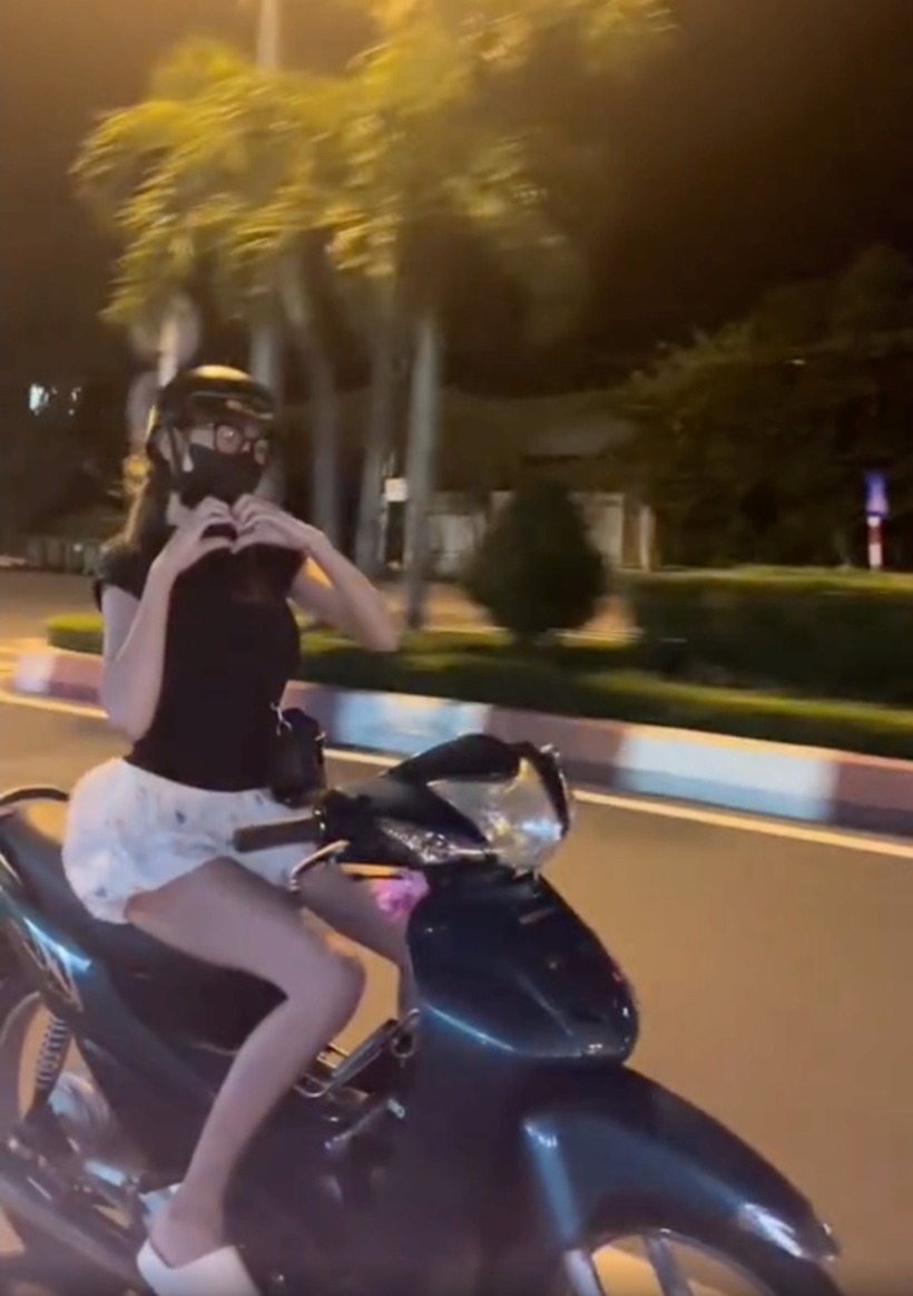 Cô gái buông tay lái để làm động tác hình trái tim. Ảnh: Người Lao Động