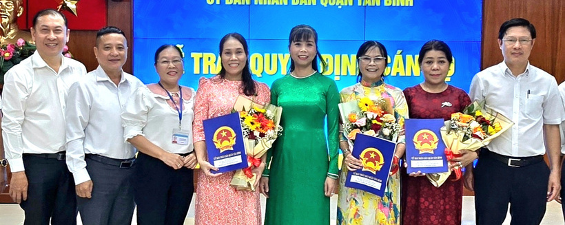 Bà Lê Thị Thu Sương (thứ 4 từ phải sang) - ủy viên Ban thường vụ Quận ủy, phó chủ tịch UBND quận Tân Bình, TP.HCM - trao quyết định điều động, bổ nhiệm 3 hiệu trưởng (người cầm hoa) của 3 trường công lập mới. (Ảnh: Tuổi trẻ)