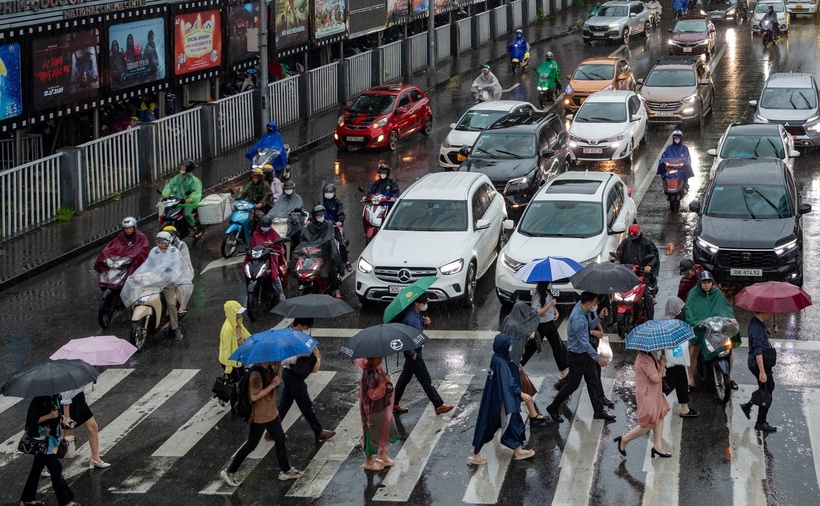 Dòng phương tiện di chuyển chậm rãi trên phố Thái Hà (Hà Nội) trong điều kiện khó khăn, người dân vội vã sang đường trong cơn mưa không ngớt. (Ảnh: Dân trí)