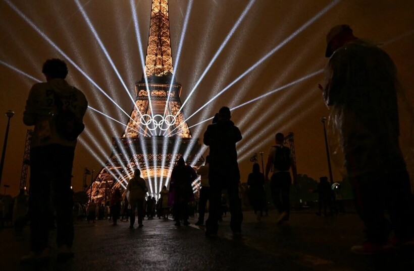 Người hâm mộ đội mưa đứng xem khai mạc Olympic. Cơn mưa nhỏ ở Paris không làm ảnh hưởng cuộc diễu hành dài 6 km của các đoàn thể thao.