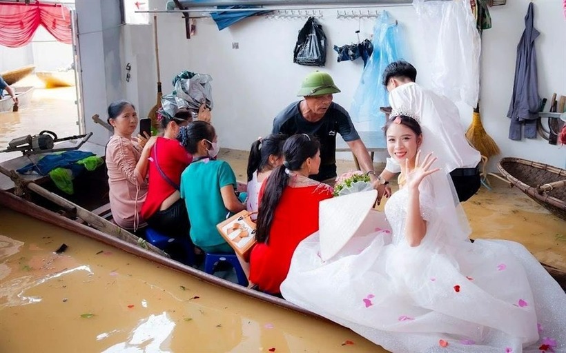 Cô dâu di chuyển bằng thuyền băng qua đoạn ngập nước. Ảnh: Phụ Nữ Việt Nam