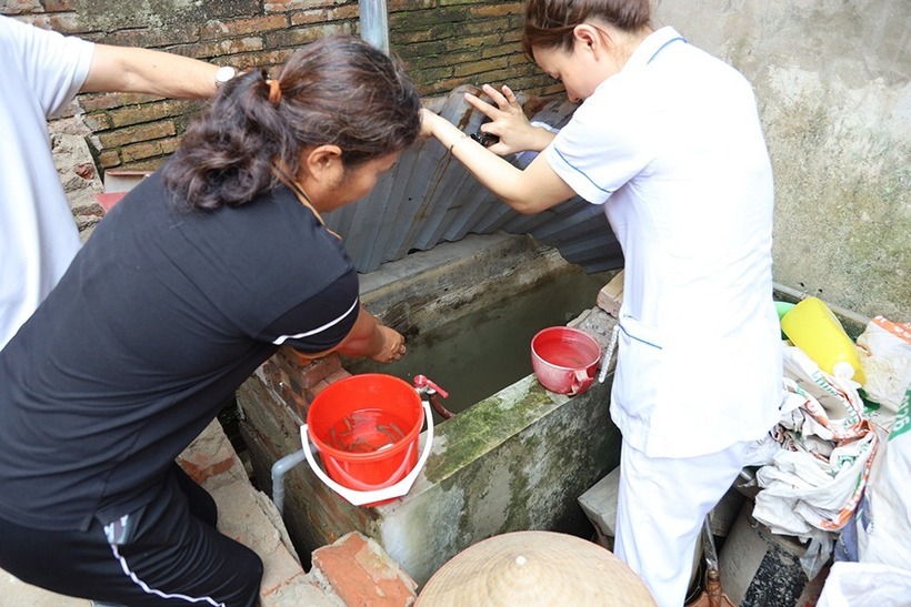 Cán bộ y tế hướng dẫn người dân cách diệt bọ gậy tránh muỗi, phòng dịch sốt xuất huyết. Ảnh: Kinh tế & Đô thị