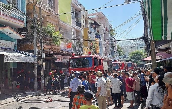 Người dân tập trung kín phía ngoài, trong khi xe cứu hỏa nối đuôi nhau tiếp nước cho cảnh sát dập lửa. (Ảnh: VNE)
