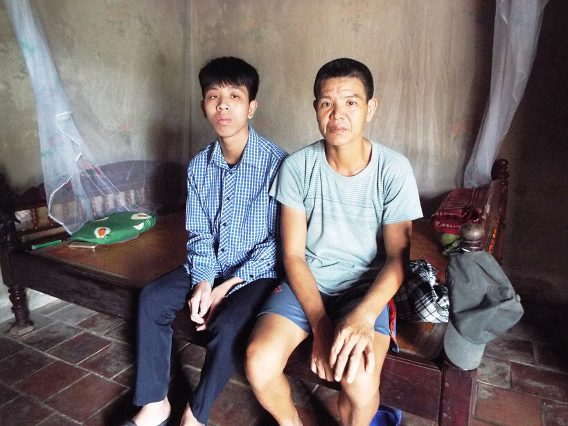 Em Hoàng Long Vũ bên cạnh người bố bệnh tâm thần. Ảnh: Vietnamnet.
