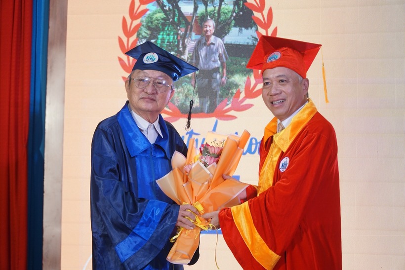 Hiệu trưởng Trường ĐH Nha Trang (áo đỏ) trao bằng thạc sĩ cho ông Nguyễn Ánh (áo xanh). Ảnh: Thanh Niên