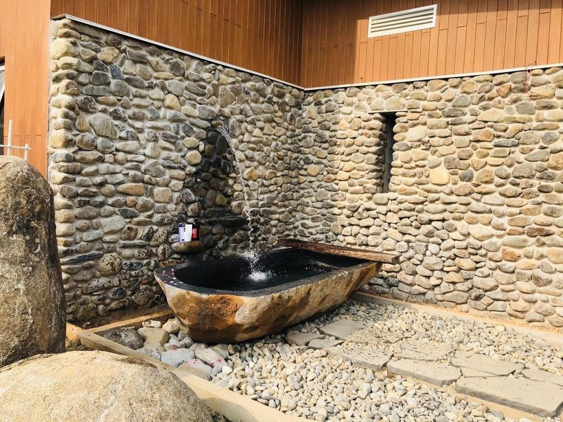 Tường của công trình được bài trí cách điệu với nhiều chất liệu khác nhau như gỗ conwood chịu nhiệt, gạch cổ,... Gam màu phá cách cũng giúp công trình nổi bật giữa thiên nhiên rộng lớn.