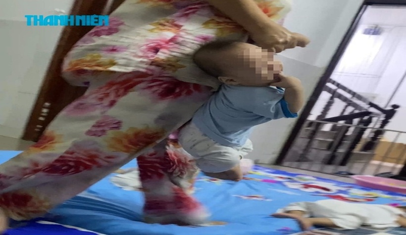 Em bé giàn giụa nước mắt khi bị bà T. xách một tay ném.