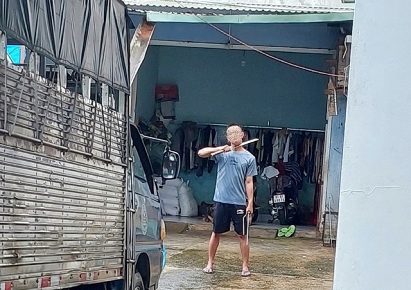 Nguyễn Thành L. kề mã tấu lên cổ dọa tự sát nếu bị khống chế. Ảnh: Người Lao Động