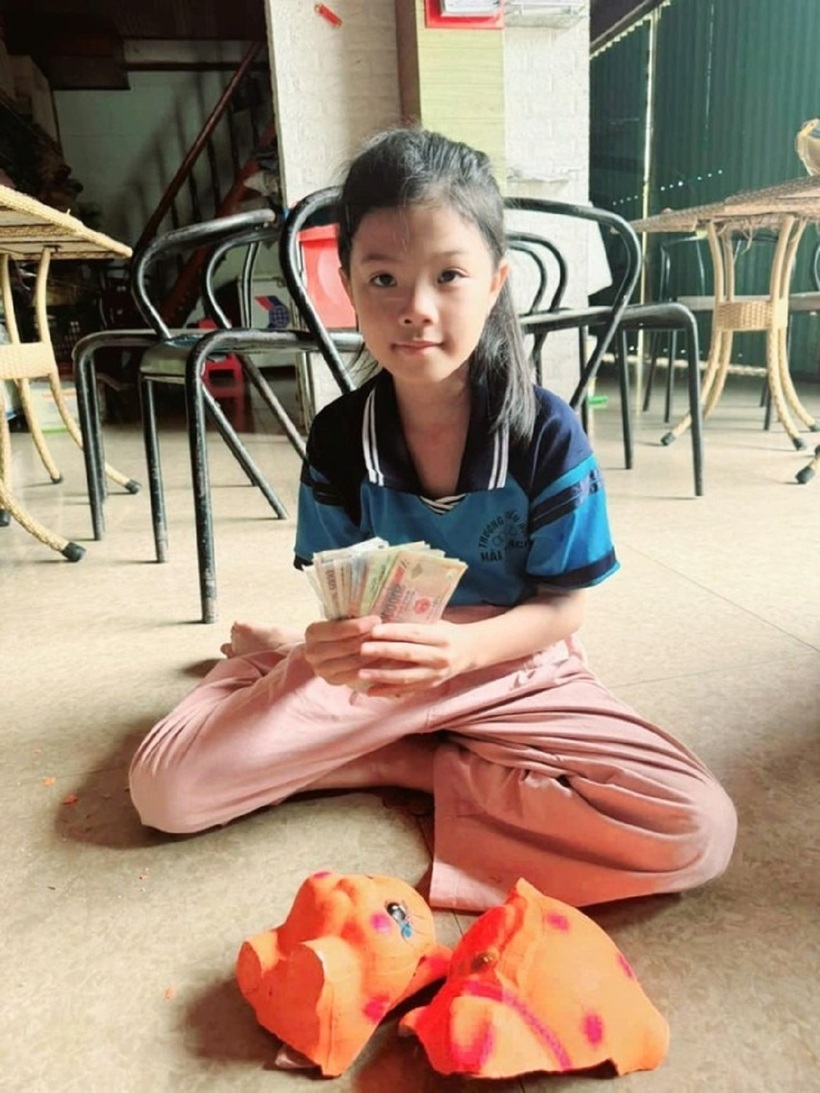 Em Lê Đan Ny cùng số tiền em đã đập heo đất để ủng hộ các bạn miền núi phía Bắc. Ảnh: Tiền phong
