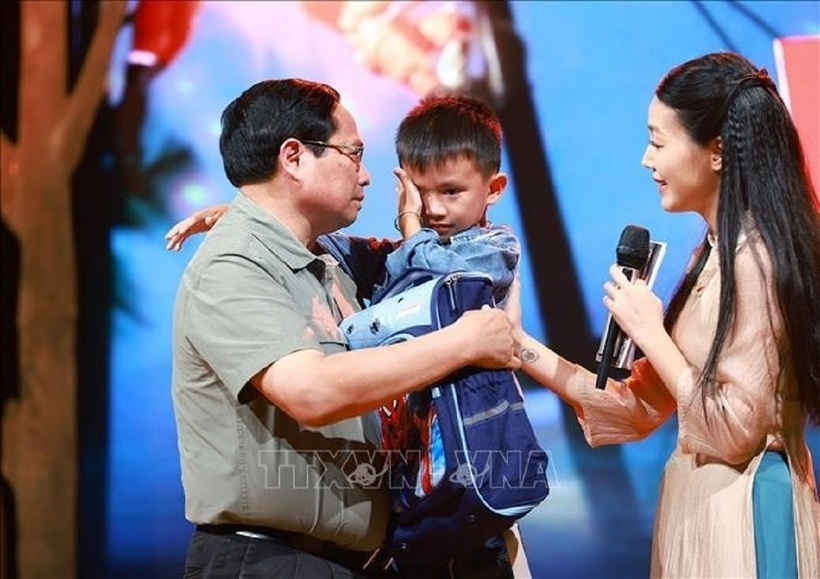 Thủ tướng Phạm Minh Chính vỗ về cậu bé Quốc Bảo. Ảnh: TTXVN