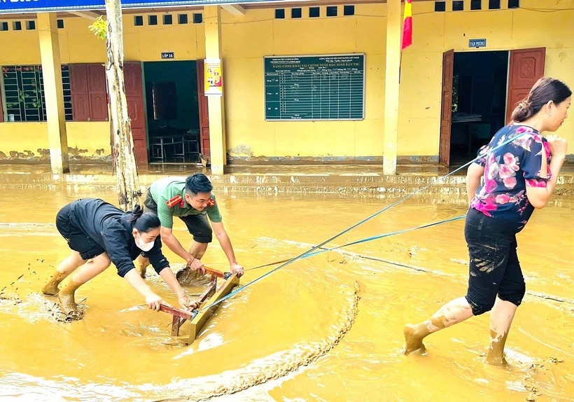 Thầy cô cùng lực lượng chức năng bì bõm lội bùn dọn trường lớp. Ảnh: VietNamnet