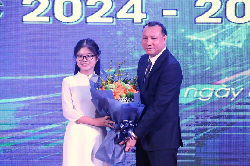 Em Nguyễn Thanh Xuân (thủ khoa khối C00 toàn quốc năm 2024, theo học ngành Sư phạm Lịch sử Trường ĐH Sư phạm Hà Nội) đại diện cho các tân sinh viên khóa 74 tặng hoa cho Hiệu trưởng Nguyễn Đức Sơn. (Ảnh: VietnamNet)