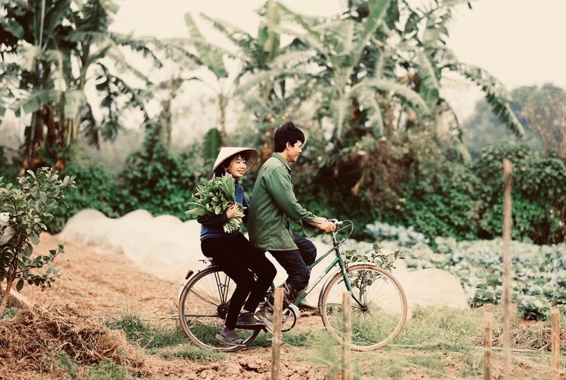 Chị Duyên ngồi sau, hai tay ôm chặt eo chồng để "theo anh ra đồng". Ảnh: Dân trí