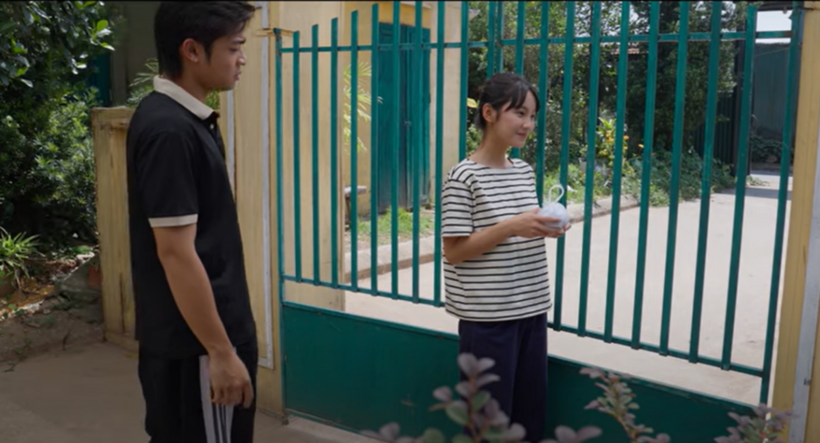 Pu đứng cười tủm tỉm khi nhận được gói xôi gấc Chải mua.