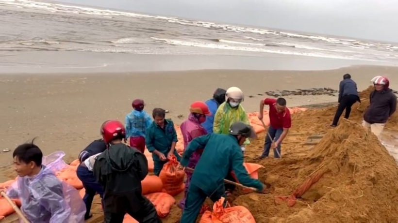 Người dân hỗ trợ xúc cát cho vào bao tải để vận chuyển tới vị trí kè biển cần gia cố. Ảnh: VietNamNet