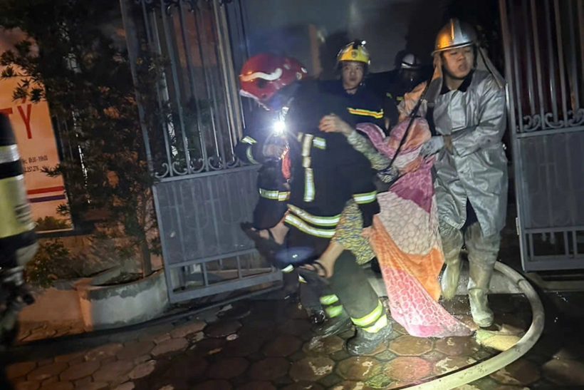 Cảnh sát trùm chăn, tránh để nạn nhân bị sặc khói, giải cứu 2 người thoát khỏi căn nhà cháy. Ảnh: Dân Trí