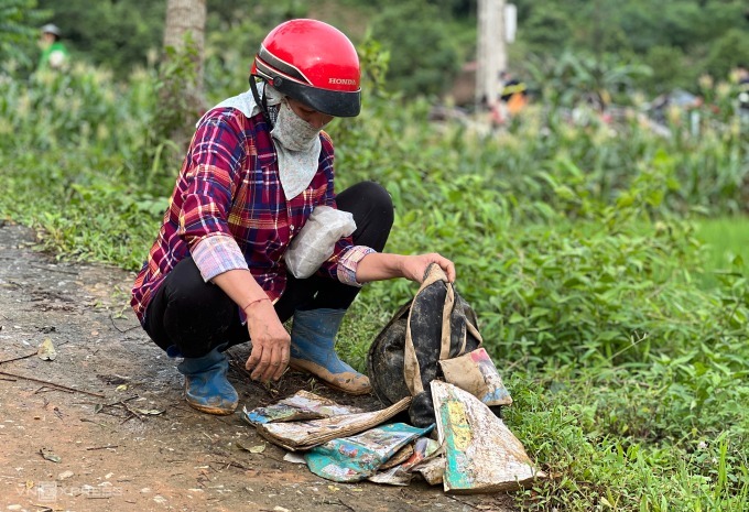 Người thân bên cặp sách còn sót lại của học trò Làng Nủ sau trận lũ quét rạng sáng 10/9. (Ảnh: VNE)