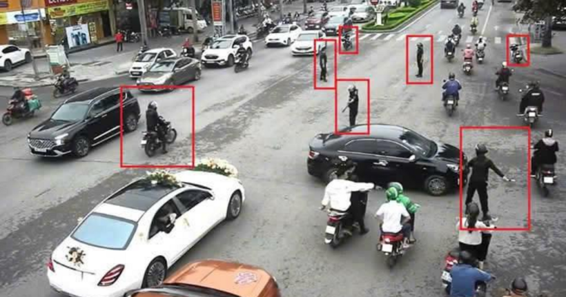 Hình ảnh nhóm vệ sĩ đứng rải rác giữa ngã tư phân luồng giao thông.
