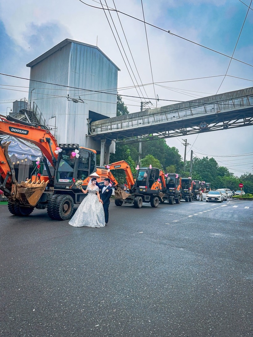 7 chiếc máy xúc nối dài, được trang trí bóng bay, hộ tống chú rể rước vợ về dinh khiến nhiều người chú ý. Ảnh: Báo Thanh niên.