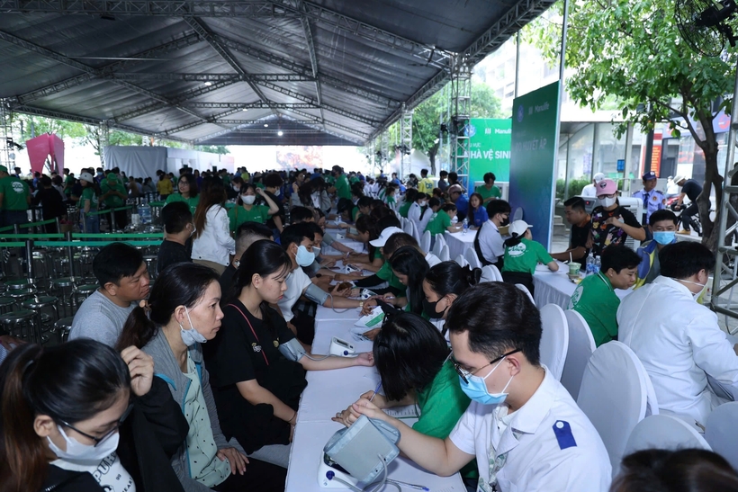 Tình nguyện viên Manulife hướng dẫn người dân thực hiện các bước khám bệnh. Ảnh Hiền Hà