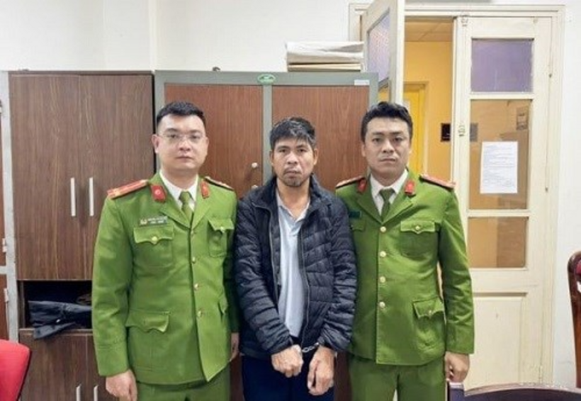 Đối tượng trốn truy nã Nguyễn Văn Thành (áo đen giữa) bị tạm giữ tại cơ quan Công an. Ảnh: Lao Động