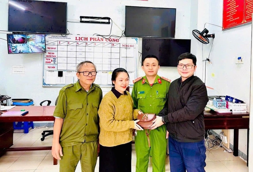 Anh Duy (phải) trả lại tài sản bị đánh rơi cho chị Trạch (trái) trước sự chứng kiến của Công an phường Nguyễn Nghiêm. (Ảnh: Công an)