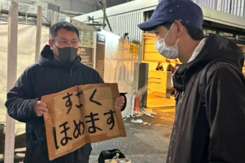 Người đàn ông bắt đầu đi khắp Tokyo, cầm tấm biển với dòng chữ: "Tôi sẽ dành cho bạn nhiều lời khen". Ảnh: Oddity Central.