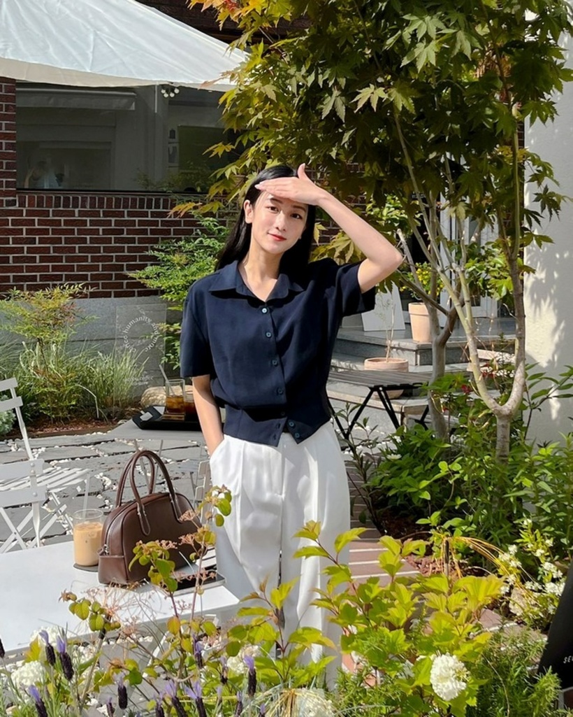 Áo sơ mi bo gấu màu xanh than kết hợp với quần trắng giúp tôn dáng mà không cần sơ vin. Ảnh minh họa.