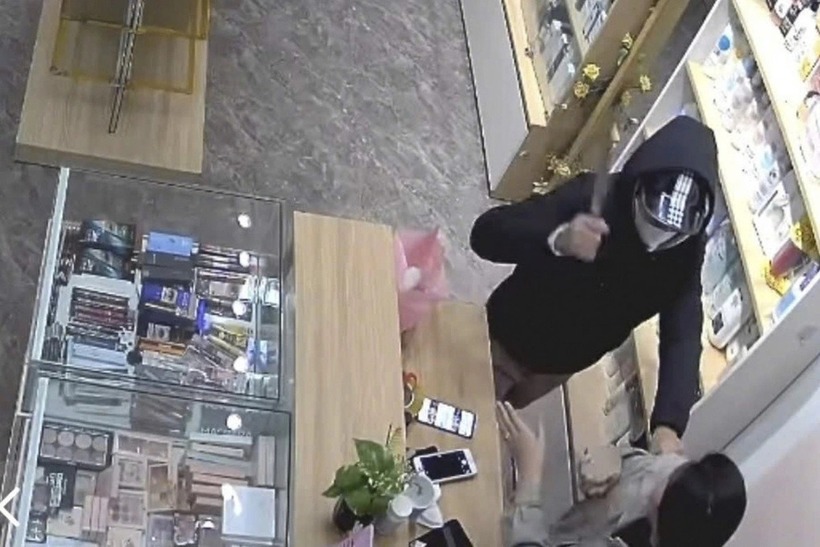 Tên cướp vung dao, đe dọa nữ nhân viên. Ảnh: Dân Việt