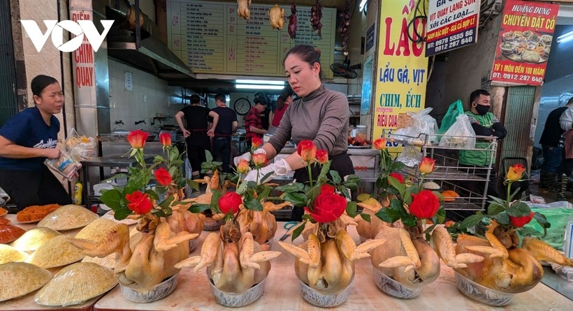 Gà trống được luộc vàng, mỏ ngậm hoa hồng đỏ được trình bày bắt mắt là sản phẩm đặc trưng của khu chợ. Ảnh: VOV.