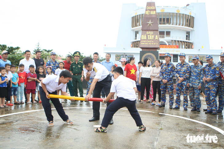 Học sinh và người dân trên đảo Đá Tây cùng các chiến sĩ hào hứng tham gia trò chơi đẩy gậy.