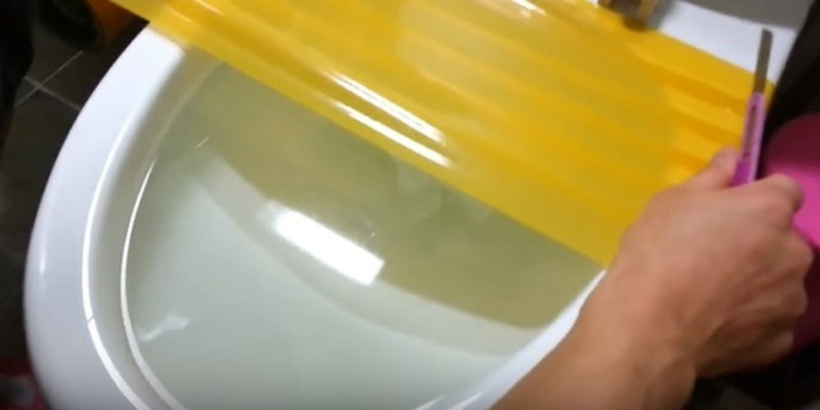 Dán băng dính kín bề mặt miệng bồn cầu, đảm bảo không có khe hở.