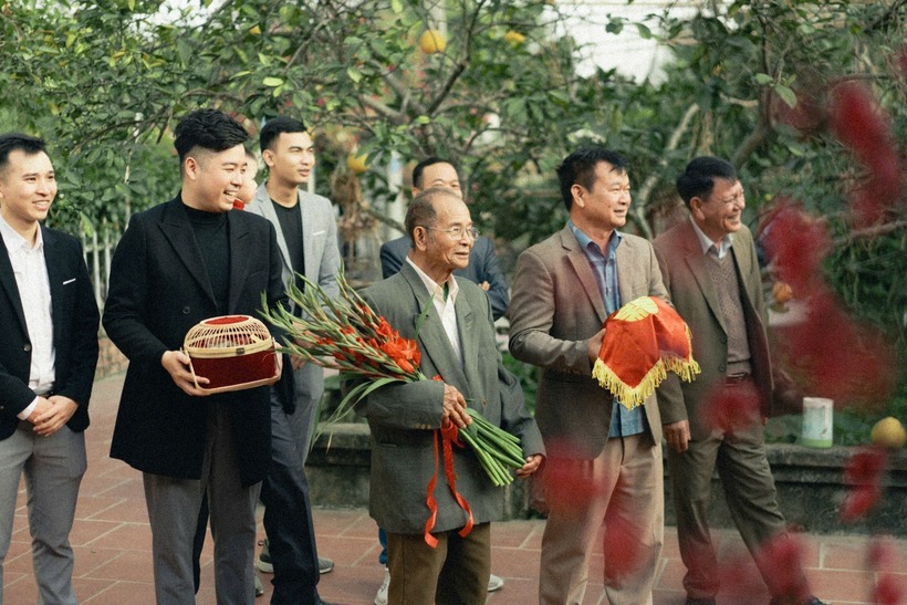 Ông Gián trong bộ đồ comple, ôm bó hoa dơn đỏ, cùng con trai bê tráp trầu cau, đại diện cho "nhà trai". Ảnh: Tạp trí Tri Thức.