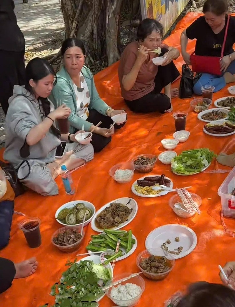 Gia đình chị Thanh Phấn trải bạt ăn dọc đường. Ảnh: Tạp chí Tri Thức.