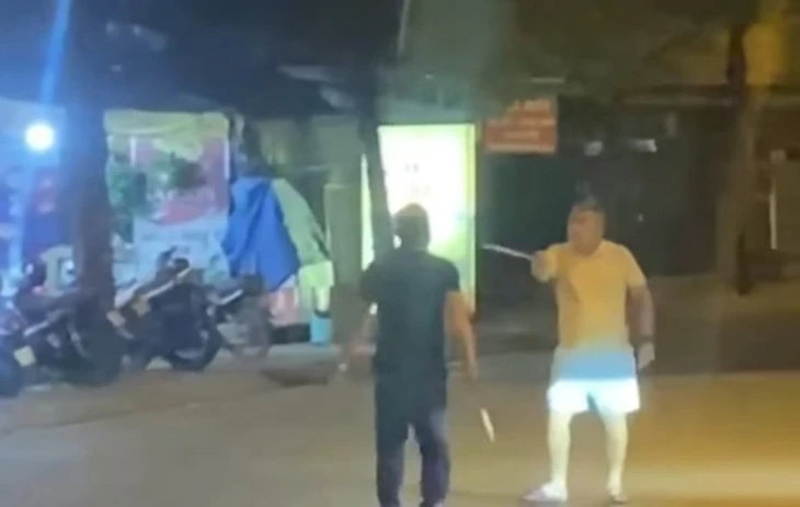 Hai người đàn ông cầm hung khí đe dọa nhau giữa đường phố. Ảnh: Tuổi Trẻ