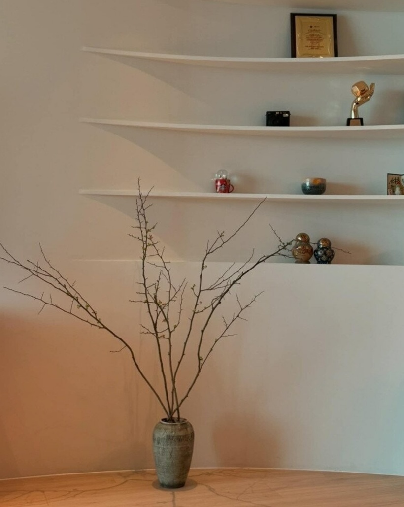 Tuy không có quá nhiều đồ đạc nhưng mỗi món đồ trên kệ đều mang giá trị kỷ niệm, từ chiếc cúp, máy ảnh cho đến những bức tượng nhỏ. Cành hoa khẳng khiu đặt trong chiếc bình gốm tạo điểm nhấn nghệ thuật.